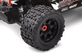 Close-up of a black off-road tire with deep tread pattern mounted on a radio control truck, featuring Team Corally XL4S 1/8 Grabber Monster Truck Tires 17mm (2) for enhanced grip on rough terrain.