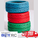 Three 1/10 rc rally car tires stacked on top of each other. Red, Blue, and Green slick racing treads for fast 4wd rc cars